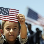 A boys shows a U.S. flag as President Barack Obama speaks about immigration at the Chamizal National Memorial in El Paso, Texas, in 2011. (Photo credit: Jewel Samad/AFP/Getty Images)