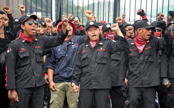 Indonesian workers shout slogans during a protest in front of Parliament building in Jakarta as lawmakers attend the plenary session to pass the mass organization bill. The workers unions vowed to appeal the controversial restriction to Indonesia's freedom of assembly laws in the Constitutional Court (Photo Credit: Bay Ismoyo/AFP/Getty Images).