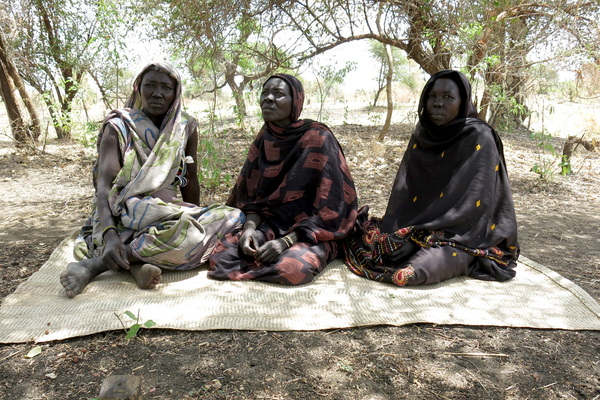 Three displaced Sudanese women finding refuge under a tree (Photo Credit: Jean-Baptiste Gallopin for Amnesty International).