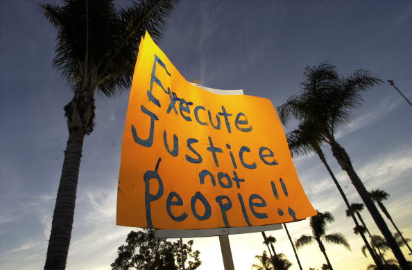 A protester holds a sign up during an anti-death penalty protest on June 18,2001 in Santa Ana, CA. (Photo by David McNew/Getty Images)
