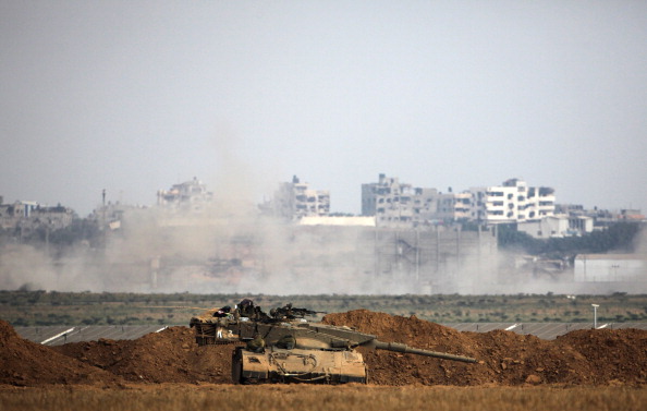 An Israeli army Merkava tank is positioned along the border in front of buildings in the Gaza Strip on July 28, 2014. (Photo credit: David Buimovitch/AFP/Getty Images)