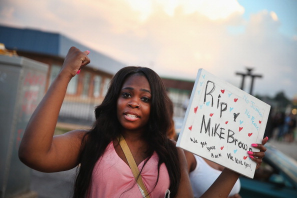 Arniesha Randall protests the killing of 18-year-old Michael Brown who was shot by police in Ferguson, Missouri. Police responded with tear gas and rubber bullets as residents and their supporters protested the shooting by police of an unarmed black teenager named Michael Brown (Photo Credit: Scott Olson/Getty Images).