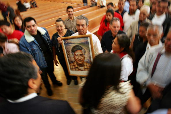 A man holds a portrait of Cesar Chavez at a mass in Los Angeles. Chavez was born on March 31, 1927. (c) David McNew/Getty Images)
