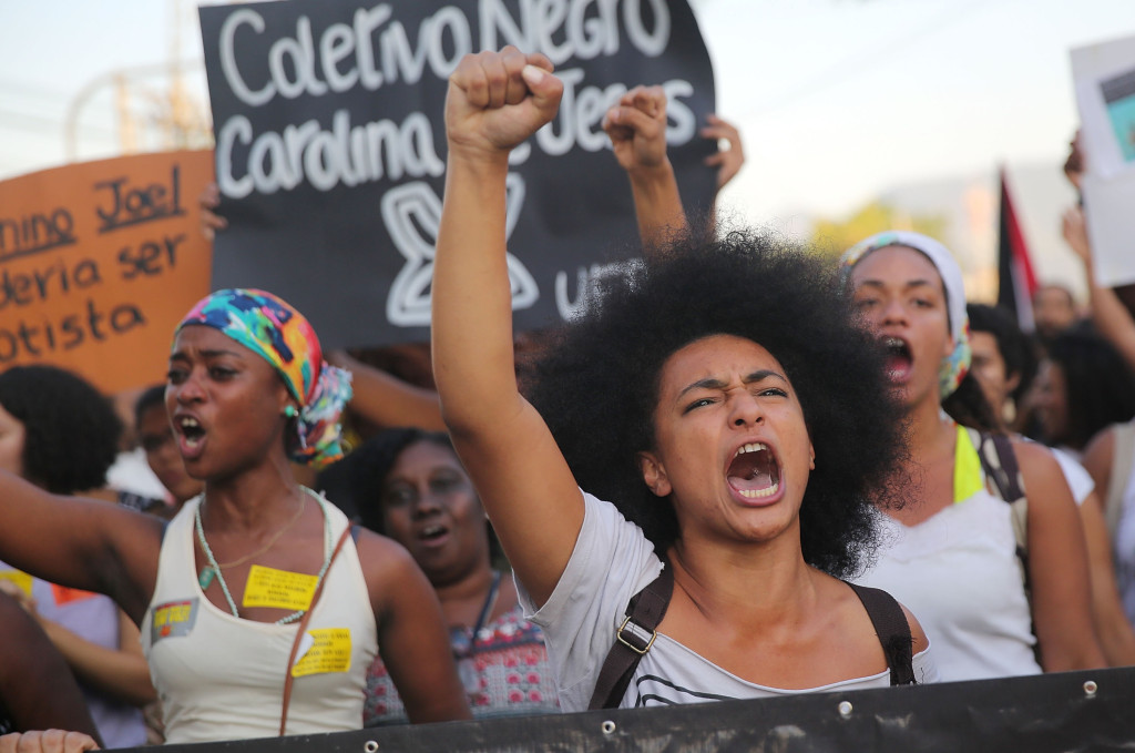 Demonstrators march through the Manguinhos favela to protest against police killings of blacks on August 22, 2014 in Rio de Janeiro, Brazil. Every year, Brazil's police are responsible for around 2,000 deaths, one of the highest rates in the world. Many of the deaths in Rio involve blacks killed in favelas, also known as slums. (Photo by Mario Tama/Getty Images)