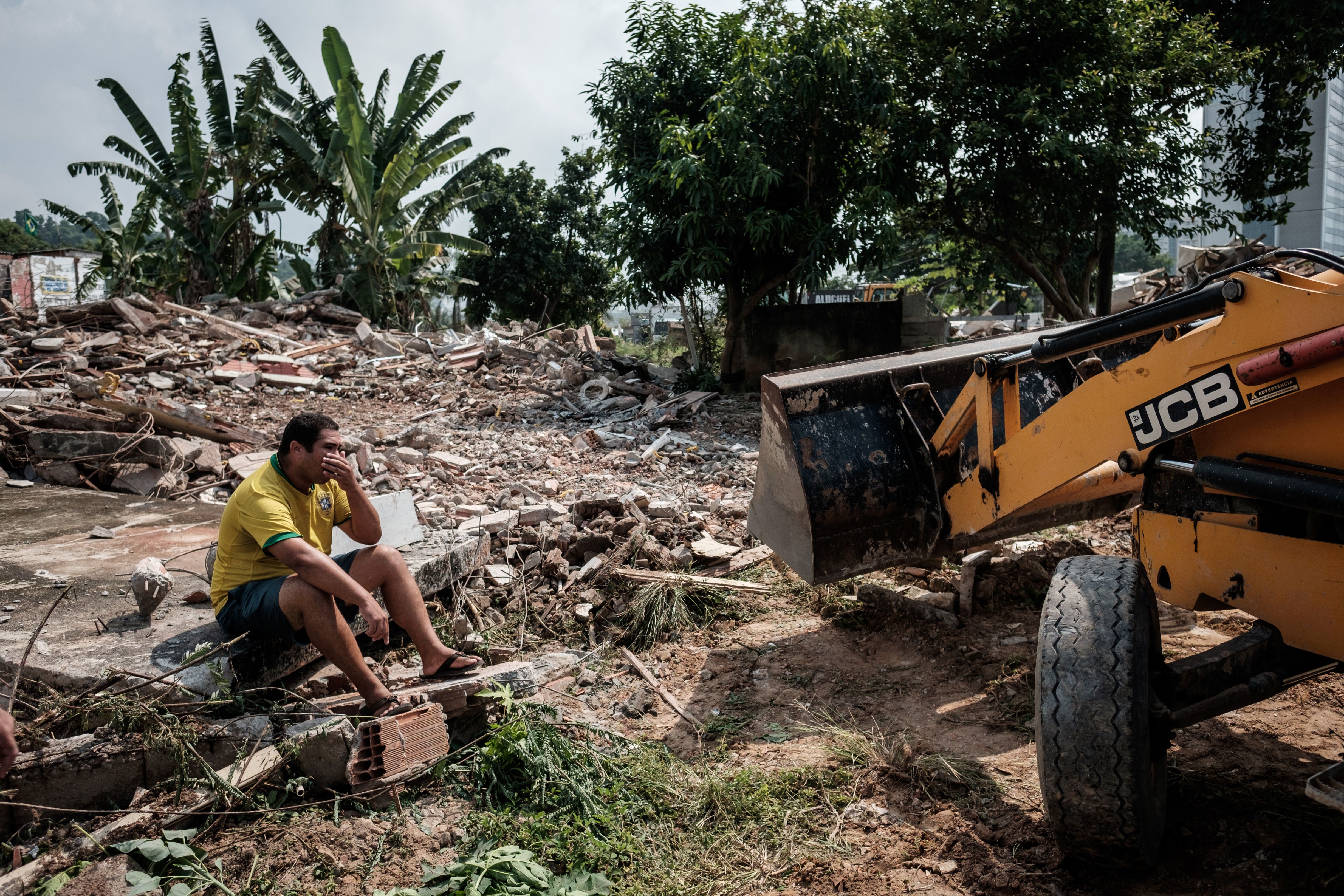 Brazilian Marcio Henrique sits on the ruins of a demolished house next door to his, at Rio de Janeiro's Vila Autodromo neighbourhood, near the construction site of the Olympic Park for the Rio 2016 Olympic Games, on March 8, 2016. Some families have refused to move out until they receive an eviction order by the municipal authorities. A passage connecting the Olympic Park and the Athletes Village is planned to be built on the site. AFP PHOTO / YASUYOSHI CHIBA / AFP / YASUYOSHI CHIBA (Photo credit should read YASUYOSHI CHIBA/AFP/Getty Images)